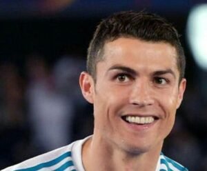 "Cristiano Ronaldo smiling and waving to fans during a match, wearing his iconic football jersey, representing one of the greatest footballers of all time."